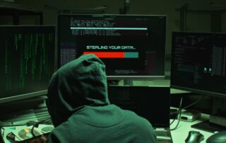 A hooded figure at a computer with a warning about data theft.
