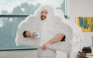 Person dressed as a cloud holding a mug in an office setting.
