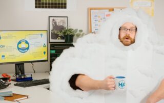 A person dressed as a cloud holding a mug in an office.